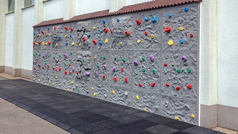 Zertifizierte Fallschutzmatten vor einer Kletterwand im freien verlegt.
