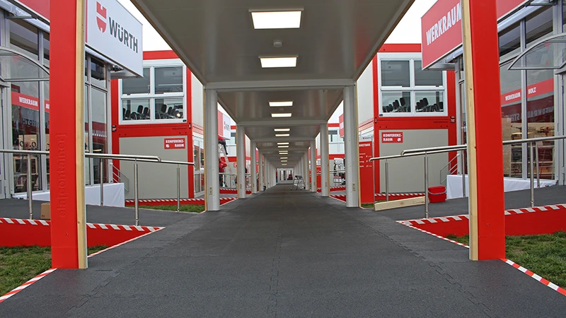 Ein überdachter Weg führt bei den Würth Informationstagen 2019 zu den einzelnen Themenbereichen. Alle Bodenflächen sind mit der schwarzen Messeboden Klickfliese belegt.
