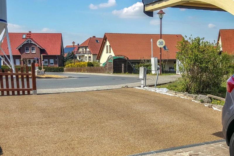 Zufahrt von der öffentlichen Straße zu einer abschüssig gelegenen Garage, gestaltet mit Gummigranulat-Platten von WARCO.